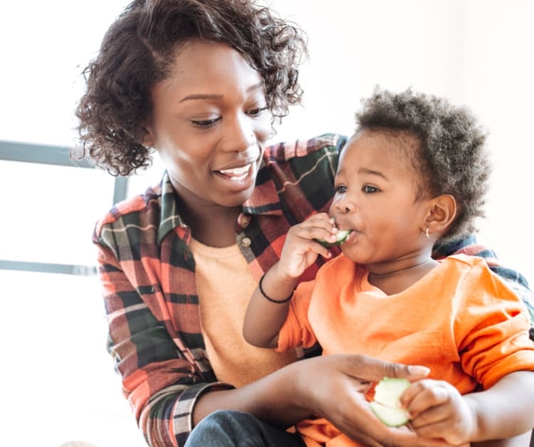 Mamá sosteniendo al niño que está comiendo
