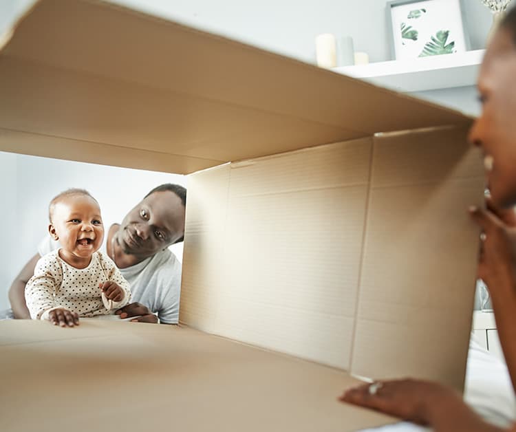 Padres jugando con su bebé y una caja