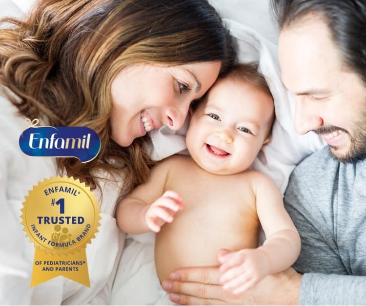 Mom and dad snuggling with baby on a bed