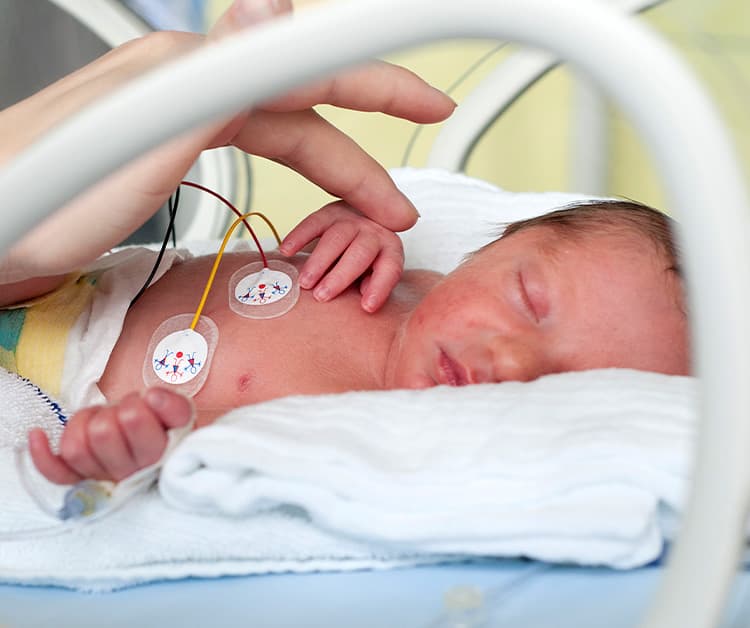 Mom comforting preemie baby in an incubator