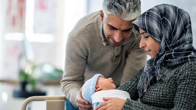 Padre y madre mirando con adoración a su bebé recién nacido.