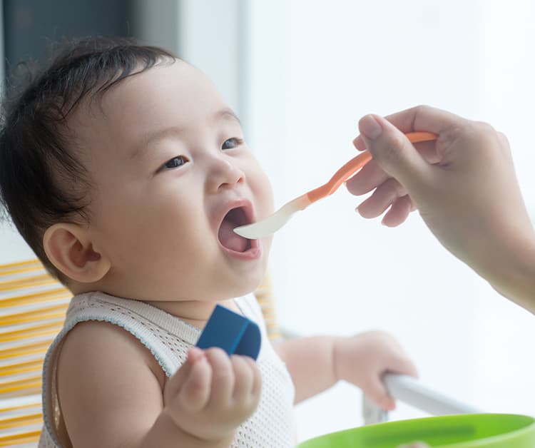 Mom spoon-feeding her baby