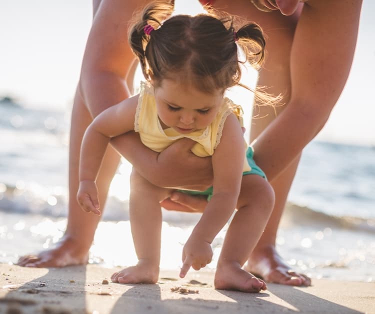 Niña jugando en la arena con su padre
