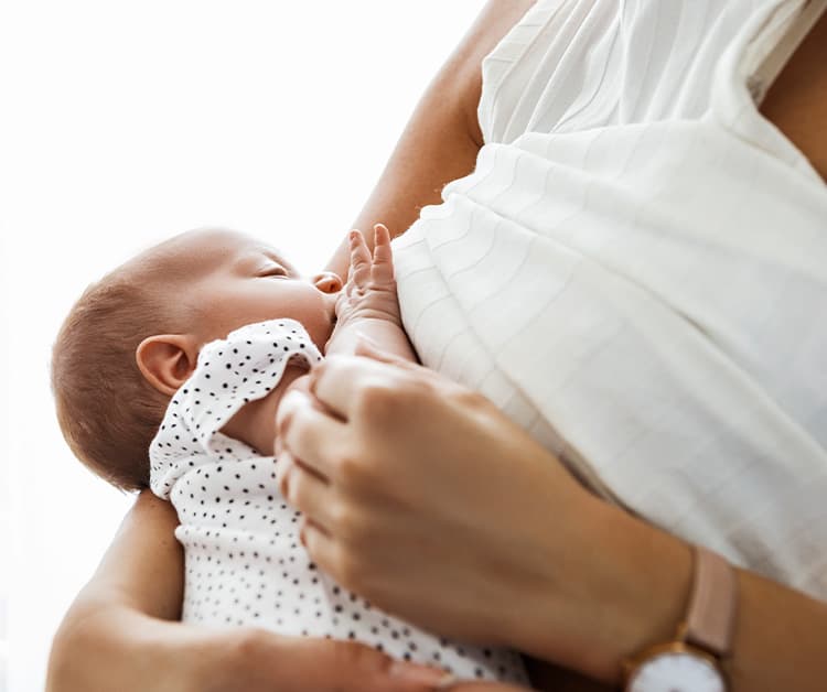 Pregnant woman holding her bump with a slight look of discomfort on her face