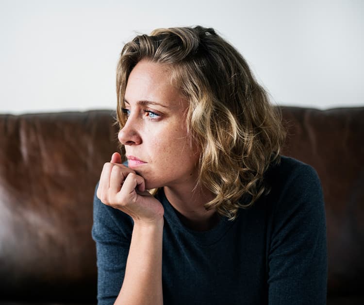 New mother looking out window while propping head up with hand