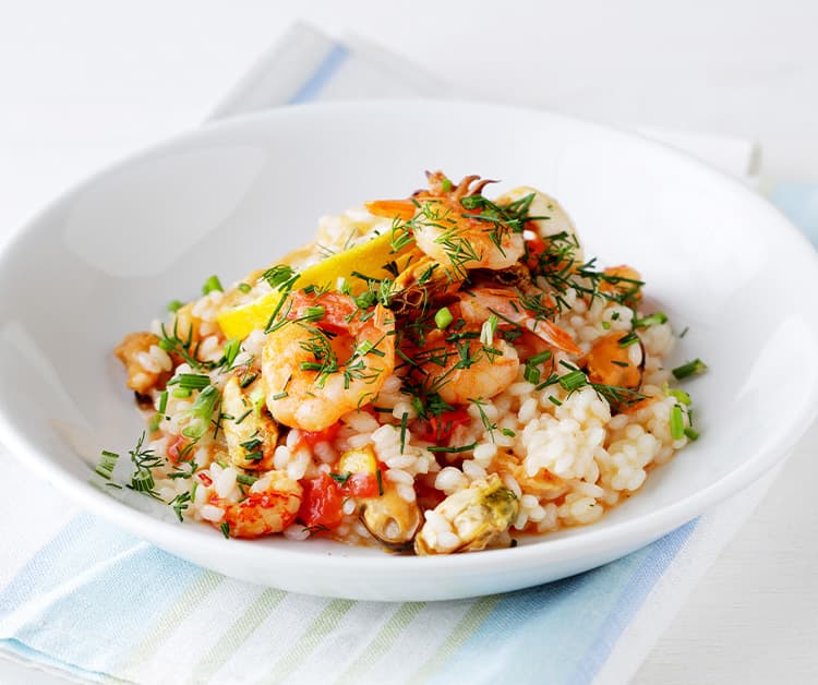 Close up of a bowl of risotto with shrimp, peas, and fennel