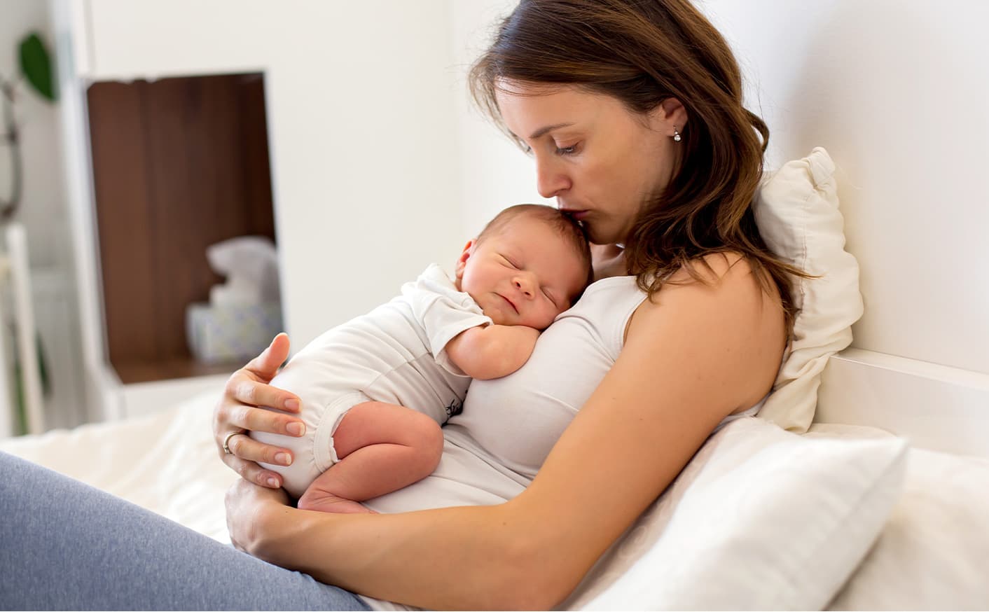 Bebe reposado en el pecho de su madre, descansando ambos en un sofa