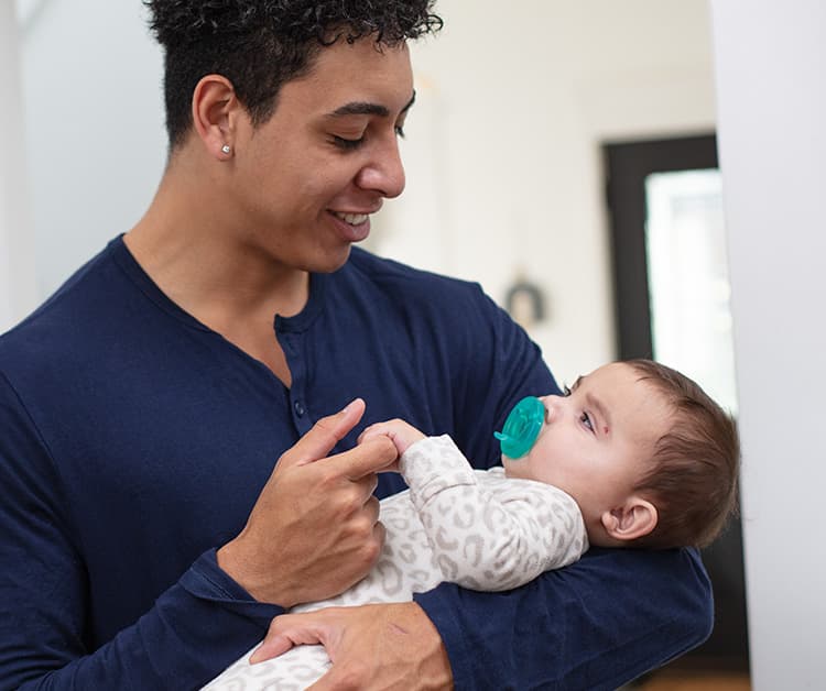 Dad cradling baby and holding baby's hand